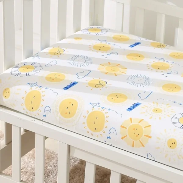 A crib with a sheet on it and the sun is drawn in blue, yellow and white.